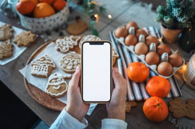 Noel yemeğinin arka planında boş ekranlı bir telefon. Mesaj için yer. Ana sınıf davetiyesi. Mutlu Noeller.