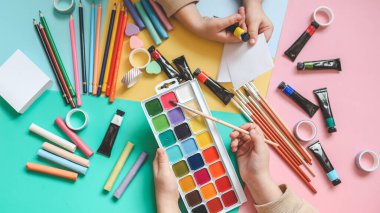 Okula dönelim. Panoramik eğitim afişi. Üst manzara, düz yatış. Masada renkli malzemeler, renkli kağıtlar. Çocukların yaratıcılık kavramı. Anaokulu eğitimi, gelişme. Okul için aksesuarlar..