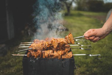 Adam gün içinde arka bahçede ızgara ızgara domuz eti yapıyor. Aile yemeği açık hava tarzı bbq etkinliği.