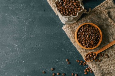 Coffee beans in a wooden plate on a black background.