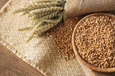 Buğday ve buğday taneleri kahverengi ahşap zemin üzerinde kase