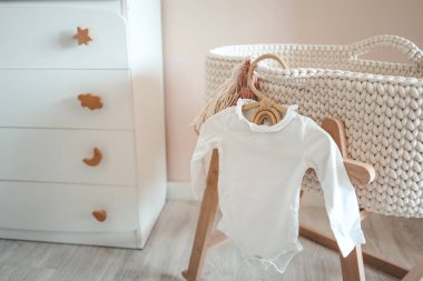 Çocuk odasındaki ahşap askıda beyaz çocuk tulumu..