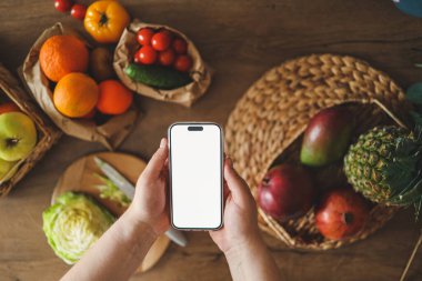 Mutfağın arka planında izole bir ekran bulunan telefon, kalori sayma konsepti ve uygun beslenme.