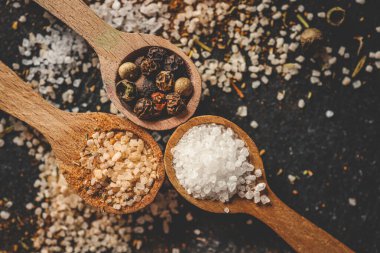 Siyah arka planda farklı baharatlı ahşap kaşıklar, afiş..