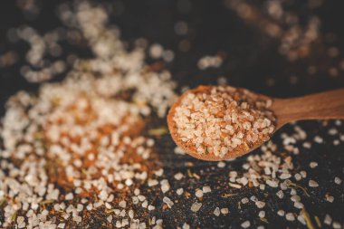 Tahta kaşık, deniz tuzu ve baharatlı siyah arka plan..