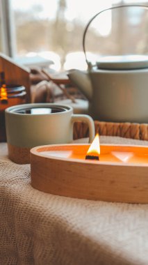 Ahşap bir kapta yanan mum, şık bir ev..