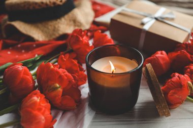 Sıcak bahar kompozisyonu, yanan mum, şakayıklar ve şapka..