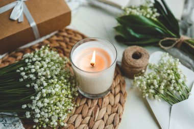 Beyaz, yanan bir mum ve bir buket vadi zambağı, doğal bir bahar fotoğrafı..