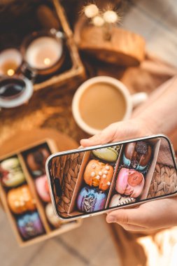 Kız telefonuyla çeşitli çeşitlilikte makaron kutusunun fotoğrafını çekiyor..