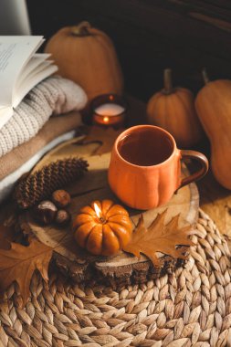 Yanan mum kabağı ve bir fincan çay arka planda bir yığın süveter, sonbahar kompozisyonu.