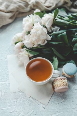 Bir fincan çay, badem kurabiyesi ve şakayık, düz bir manzara. Günaydın konsept.