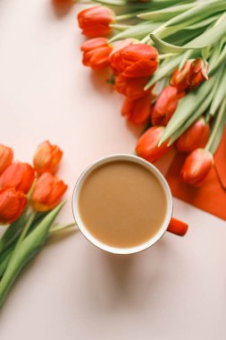 Bir fincan kahve, bir buket kırmızı lale ve dizüstü bilgisayar manzaralı düz, şenlikli arka plan.