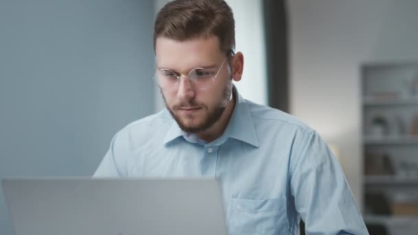 年轻坚定的男性商人 戴着眼镜 在办公室的笔记本电脑上工作 — 图库视频影像