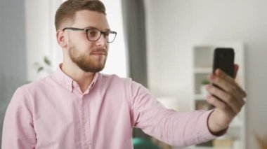 Genç yakışıklı iş adamı akıllı telefonunda video kaset ile Freinds 'le konuşuyor. Uzak iletişim