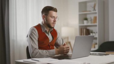 Yakışıklı, kararlı bir erkek masada oturuyor ve bilgisayarında video kaset var. Modern girişimci, uzaktan kumandalı şirket çalışanı video aracılığıyla iş görüşmesi yapıyor..