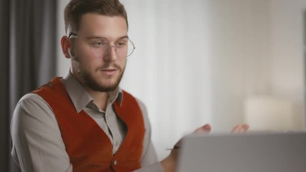 戴眼镜的英俊男子坐在办公桌前 和同事一起在笔记本电脑上进行视频通话 通过视频通话远程公司员工在商务会议上的发言 — 图库视频影像