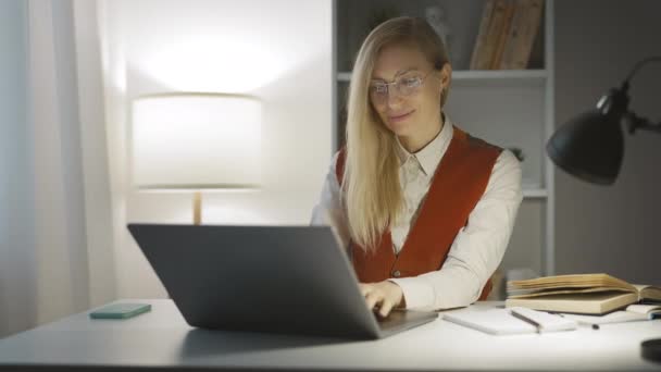 漂亮的美女 金发碧眼的女士在笔记本电脑上工作 与朋友在网上聊天 微笑着 晚上有空 — 图库视频影像