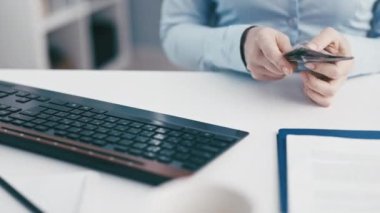 Resmi kıyafetli kadın, ofis masasında çalışan aletlerle dolar sayan banknotlar sayıyor.