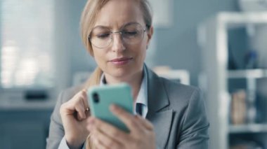 Akıllı telefondaki verileri karıştıran olgun bir iş kadını, finansal işler için taşınabilir bilgisayar kullanan başarılı bir kadın.