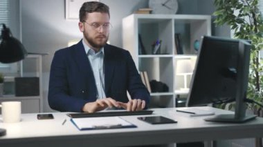 Ofiste bilgisayar klavyesinde yazan gözlüklü adam, uzaktan kumandalı başarılı girişimci, iş başarısı konsepti