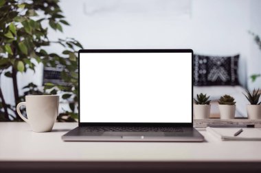 Fotokopi için beyaz ekranı olan modern bir laptop, bir fincan sıcak kahveyle rahat bir ev ışığı.
