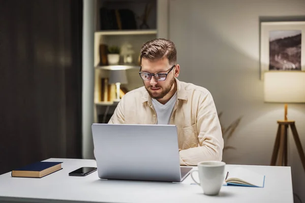 男性坐在办公桌前 拿着笔记本电脑 浑身湿透 下班后尽量放松 对所做的工作感到满意 图库图片