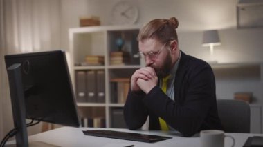 Handsome thoughtful mature man working on computer, bearded businessman has dilemma