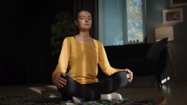 Kadın akşam yogası, meditasyon, namaste, güneşe veda ediyor, sıcak odasında pencerenin yanındaki güneş ışığıyla dolup taşıyor.