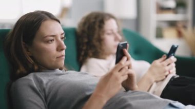 İki genç ve güzel kadın gün içinde evinde, kanepede oturmuş, akıllı telefon ekranına bakıyor ve sıkılmış, yalnızlık çekiyor ve birbirini görmezden geliyor.
