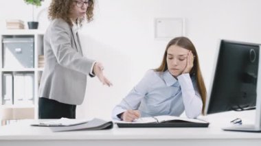 Ofisteki kadın çalışanlar işyerlerinde yorgun hissediyorlar ve patronun saldırganlığına karşılık vermeden veya tepki vermeden defterlerine çiziyorlar.