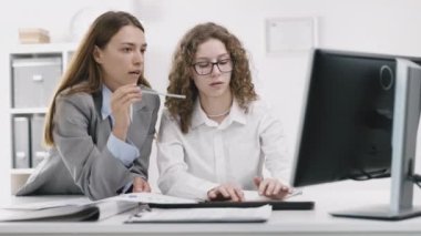 Ofisteki iki kadın takım çalışması bilgisayardaki mali verilerle birlikte grafiklerdeki her şeyi kontrol ediyor.