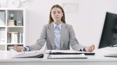 Cazibeli iş kadını, bilgisayar masasında yoga pozu verirken, mavi gömlekli ve ceketli yorgun bir işçi ofiste nefes alma egzersizi yapıyor.