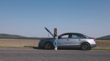 Öfkeli genç bir kadın eve dönerken yolda bozuk bir arabanın önünde akıllı telefon kullanır ve servis sağlayıcıyla durumu konuşur.