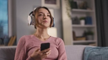 Güzel gülümseyen bir kadın müzik dinlemekten hoşlanır, telefon kullanırken kulaklıkla dinlemekten, şarkı eşliğinde sallanmaktan, ritim içinde el sallamaktan