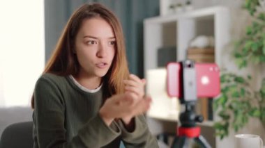 Akıllı telefondan konuşan genç, pozitif bir kadın, masada oturmuş, ekranda arkadaşına komik hikayeler anlatıyor.