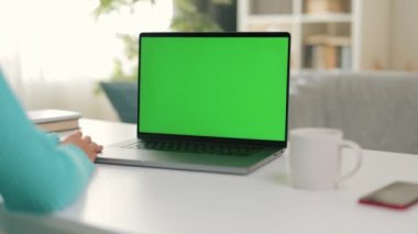 Yakın plan görüntü, elleri klavyede dizüstü bilgisayar ekranı, kroma tuşlu yeşil ekrana bakarken bir kadının dizüstü bilgisayar kullandığını gösteriyor.