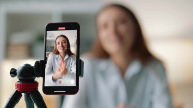 Kadın blogcuların takipçilere hikayeler anlattığı, ilginç içerikleri paylaştığı, masa başında oturup elleriyle el kol hareketi yaptığı akıllı telefon ekranı.