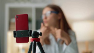 Gözlüklü ve resmi giyinmiş ciddi ve başarılı bir kadının telefon görüntüsü finans ve iş hakkında kendi video bloğunu oluşturuyor.