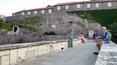 Adriyatik Denizi 'ndeki St. Stefan Sahili manzarası. Turistler tarihi kaleyi keşfeder ve güzel manzaranın tadını çıkarırlar..