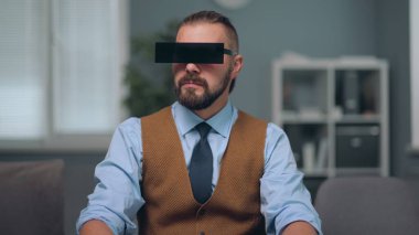 Bir adam holografik ekranları izliyor, siyah dikdörtgen gözlük giyiyor.