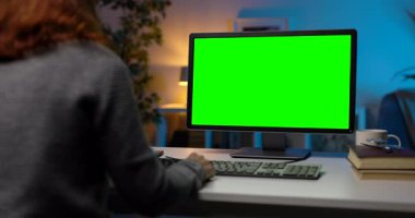 Karanlık atmosferli oturma odasında oturan bir kadının bilgisayarını uzaktan kontrol için kullanması. Renkli anahtar görüntülü modern bilgisayar.