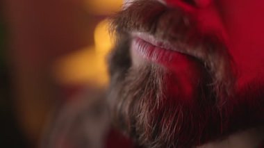 Vahşi beyaz adamın mükemmel sakalına eliyle dokunduğu yakın plan. Arkaplanda koyu renkli ışık.