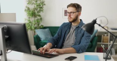 Ofiste otururken bilgisayar klavyesinde yazan profesyonel programcı. Genç sakallı adam masasında otururken yeni veri kodu üzerinde çalışıyor..