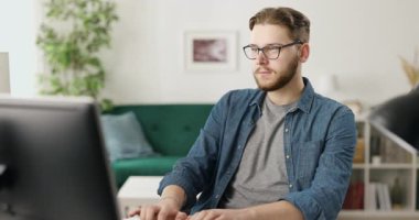 Gözlüklü hoş beyaz adamın portresi evde kalırken yeni bir program kodluyor. Masada oturan ve modern bilgisayarda yazan yakışıklı adam..