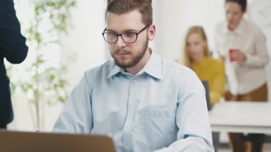 Genç sakallı adam ofiste kod yazıyor.