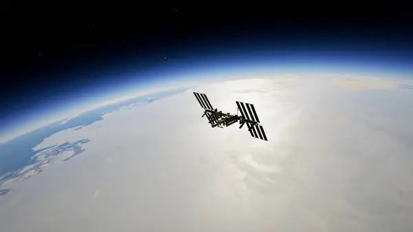 Uluslararası Uzay İstasyonu, Dünya 'nın atmosferine ve uzayına karşı siluetlendi. Arka planda güneş panelleri görünür ve parlak güneş ışığı vardı.. 