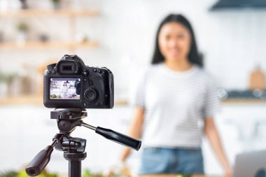 Genç bir Asyalı kadın beslenme uzmanının video içeriğini video bloğu için kameraya kaydetmesi ev mutfağında duruyor, sağlıklı gıda konsepti. Canlı yayın, canlı yayın