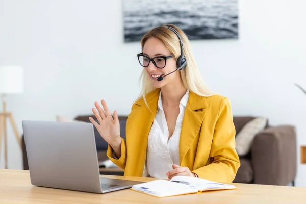 stock image Young woman in headset having in video meeting communicates with employees or the client online using laptop computer. Smiling female agent or support worker consults a client