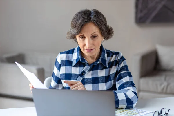 Businesswoman having video meeting with employees or partners using laptop for remote work. Successful aged female communicates online sitting in the office