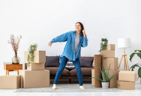 Young happy woman dances with happiness after moving into her new house or apartment. Funny Cheerful female for happiness after buying a new home. Rental housing